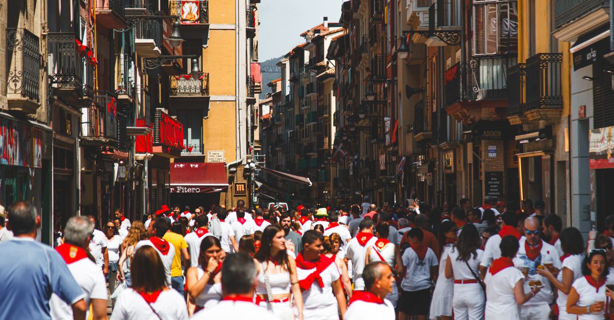 Running of the Bulls 2026: San Fermin Festival Guide in Pamplona 9 A bustling street in Pamplona, Spain, during the famous San Fermin festival, capturing crowds in traditional white with red scarves.