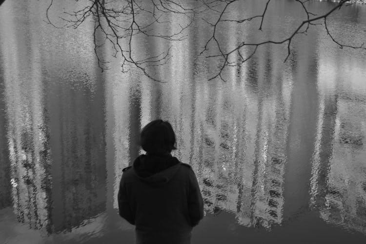 Man Looking At The Reflection Of A City In A Puddle In Black And White