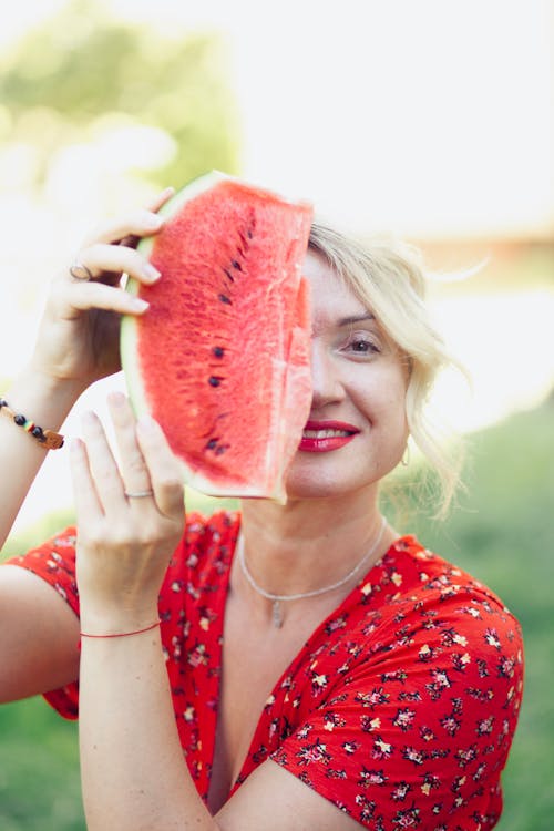 A woman in a red dress holding a watermelon