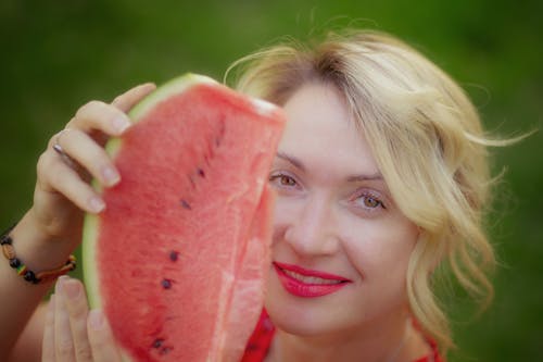A woman holding up a slice of watermelon
