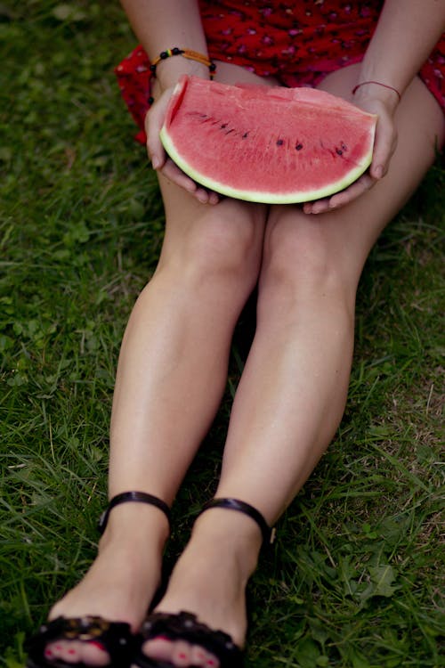 A woman in high heels holding a watermelon