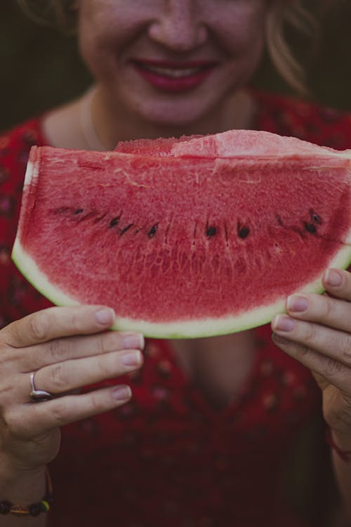 A woman holding up a slice of watermelon