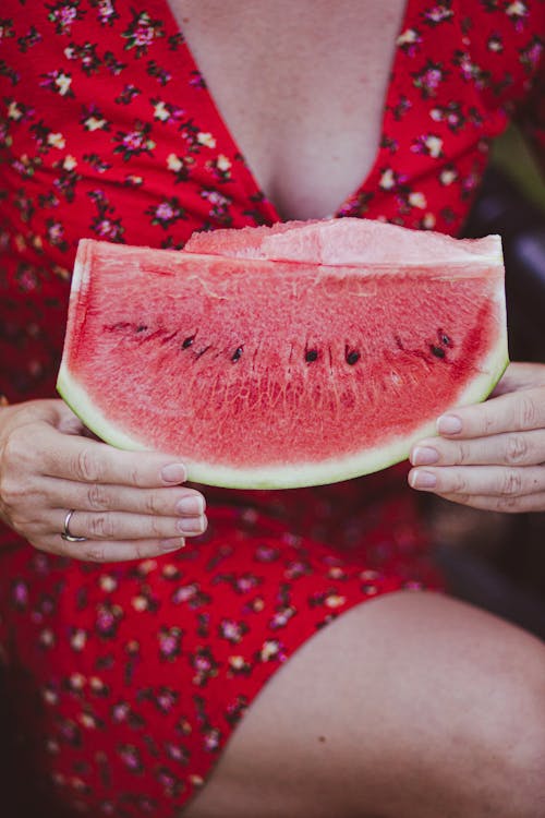 Woman in red dress holding up a slice of watermelon