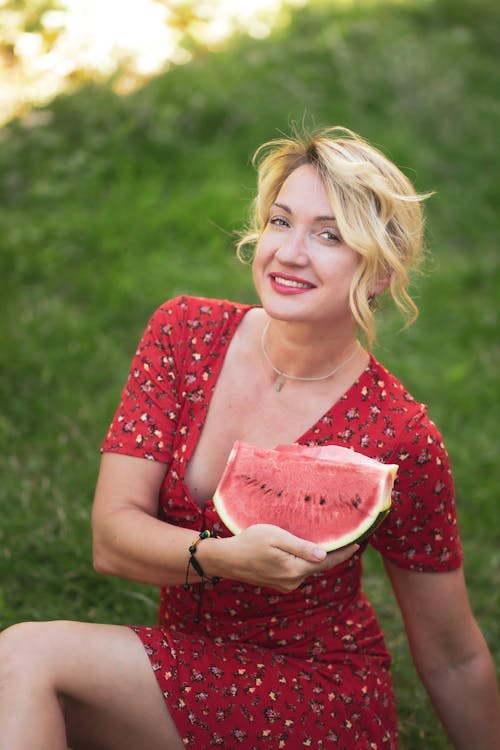 A woman in a red dress holding a watermelon