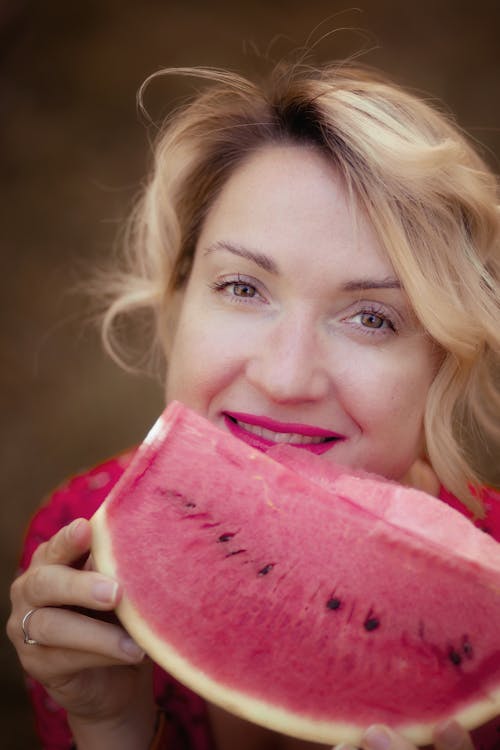 A woman is holding a slice of watermelon in her hand