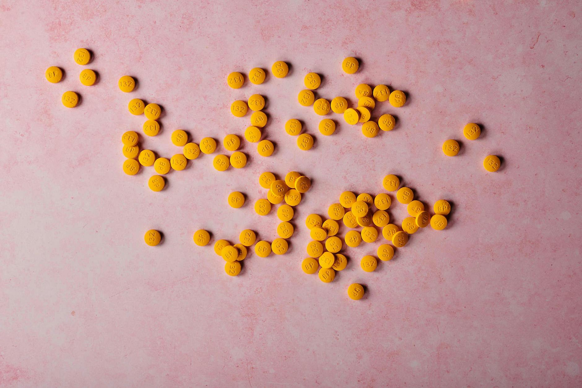 Yellow Beelith Pills Lying against a Pink Background