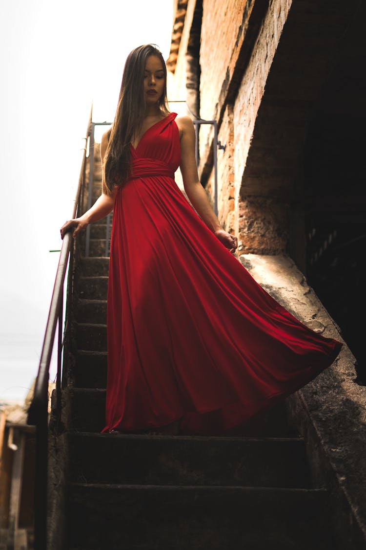 Woman Wearing Red Dress Standing On Staircase