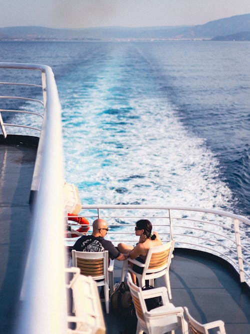 Free A Couple Sitting on a Boat during a Cruise  Stock Photo