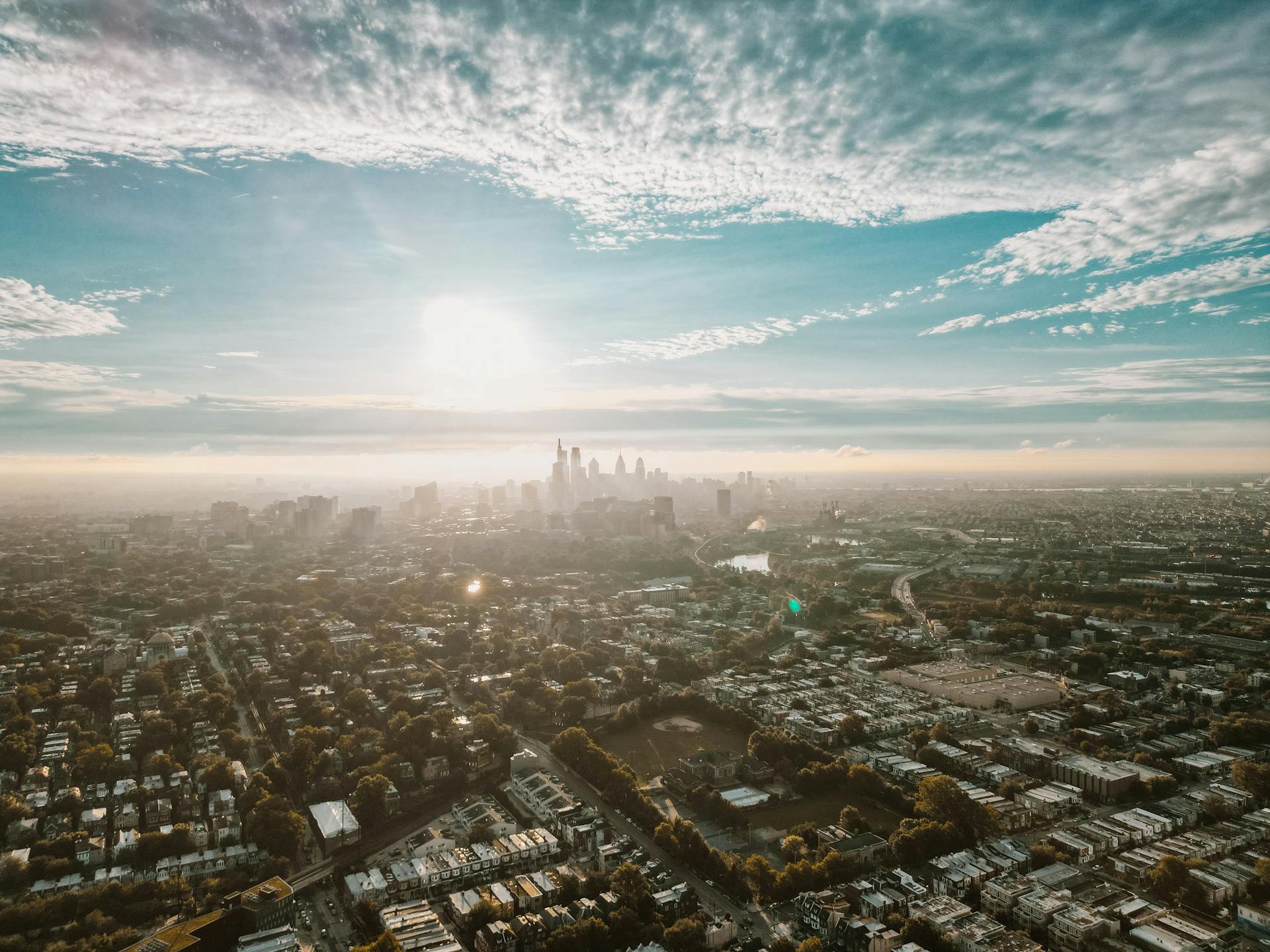 Stunning aerial view of Philadelphia cityscape with the sun rising over the horizon, highlighting the urban landscape.