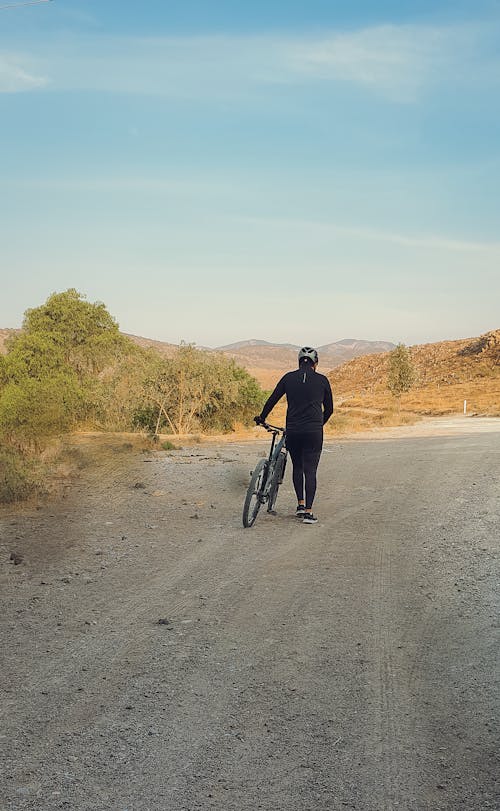 Man Walking with Bicycle on Dirt Road