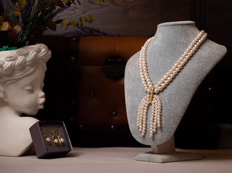 Luxurious pearl necklace displayed elegantly on a bust alongside pearl earrings.
