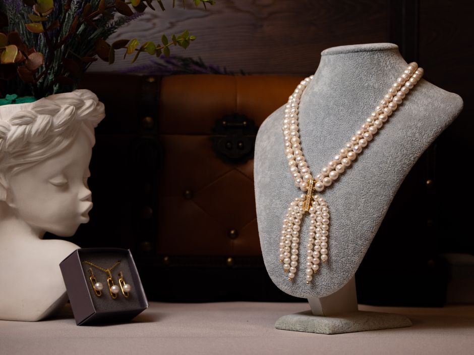 Pearl necklace displayed on a bust alongside matching earrings