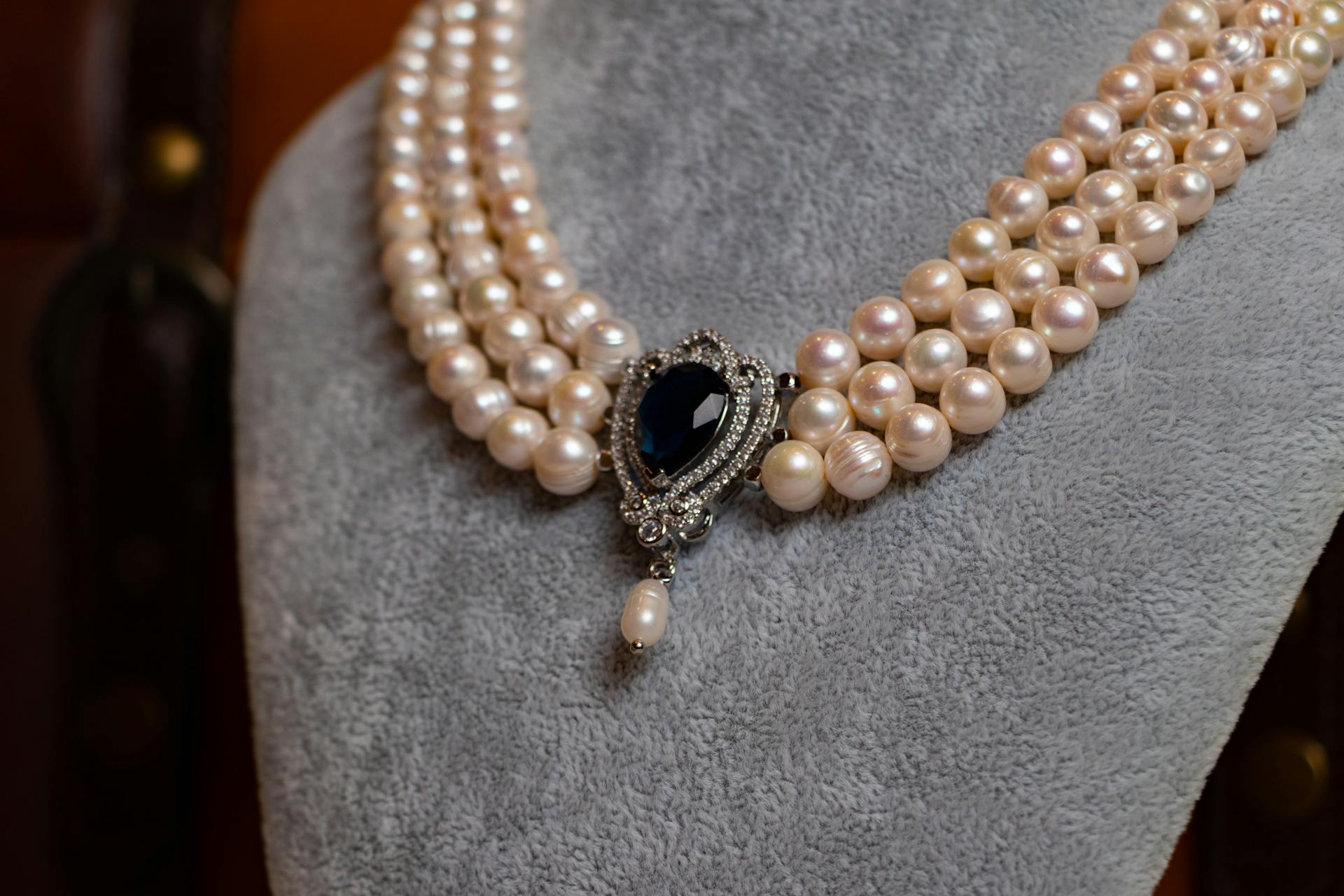 Close-up of a vintage pearl necklace with an ornate sapphire pendant, showcasing luxury and elegance.