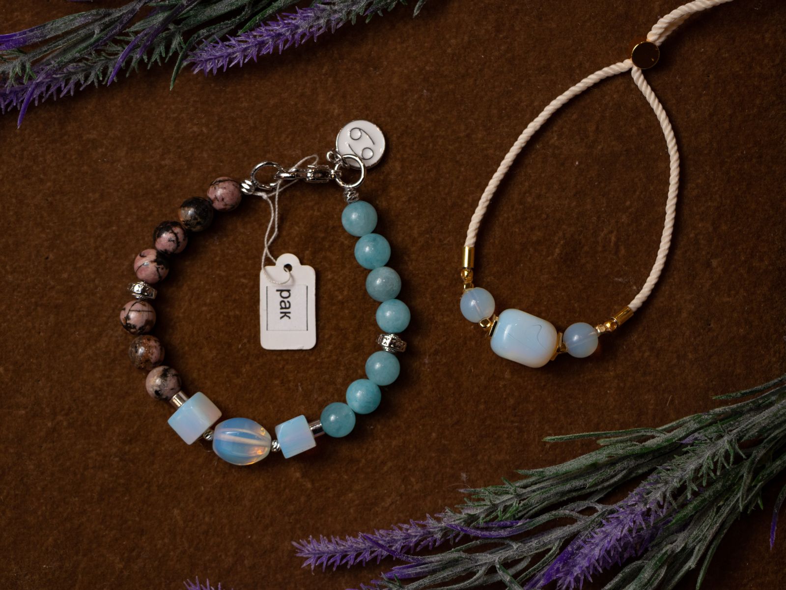 Two handmade beaded gemstone bracelets displayed on a brown textured surface