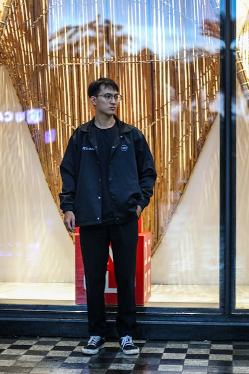 Portrait of a Young Man Wearing a Black Jacket Standing in front of a Store Window