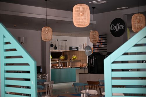 Free An inviting café interior featuring hanging lamps, teal decor, and a grill & pizza section. Stock Photo