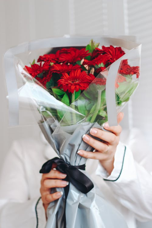 Hands of a Female Florist Holding a Bouquet of Red Flowers