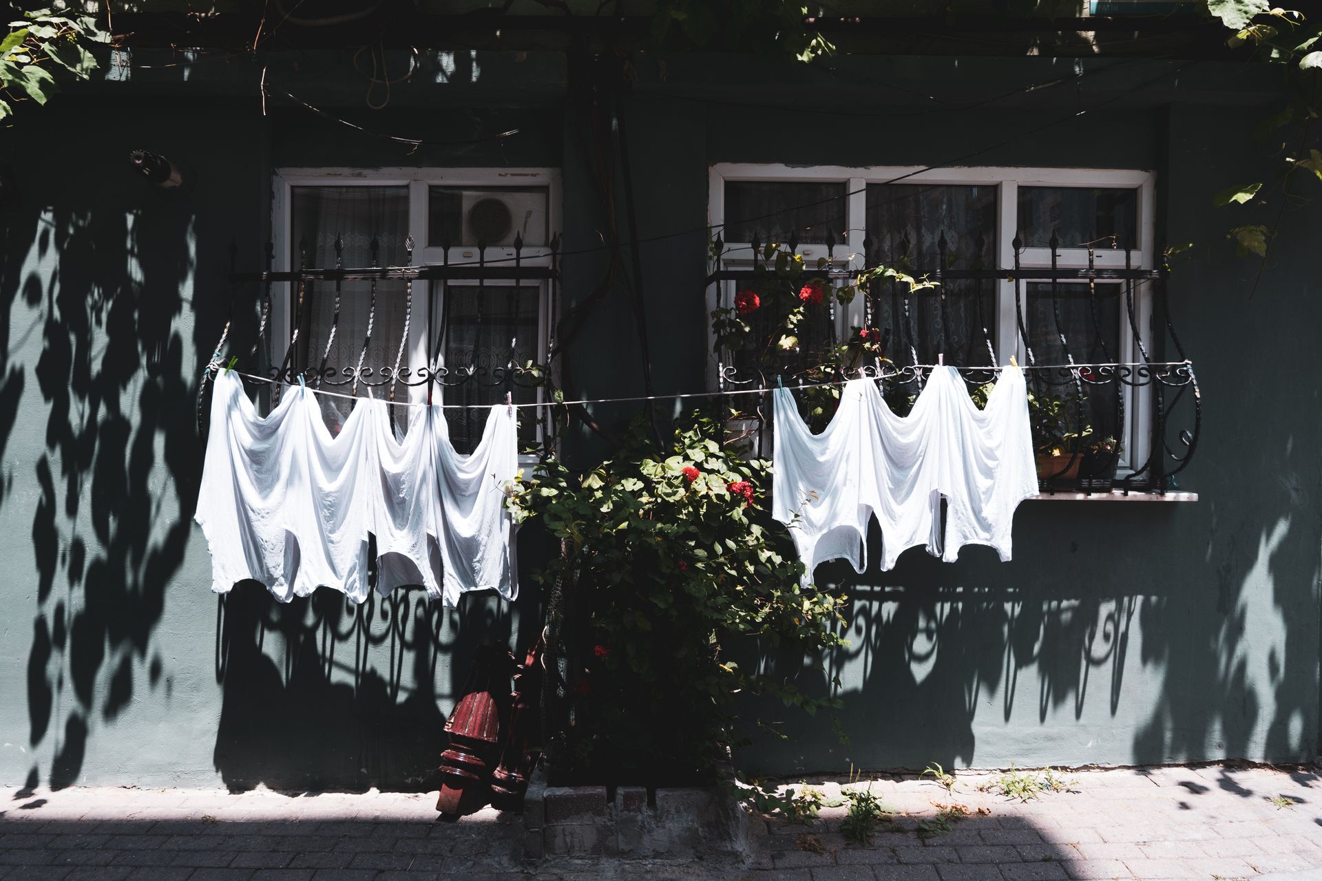 White clothes drying outside a house amid summer sun and vibrant shadows.