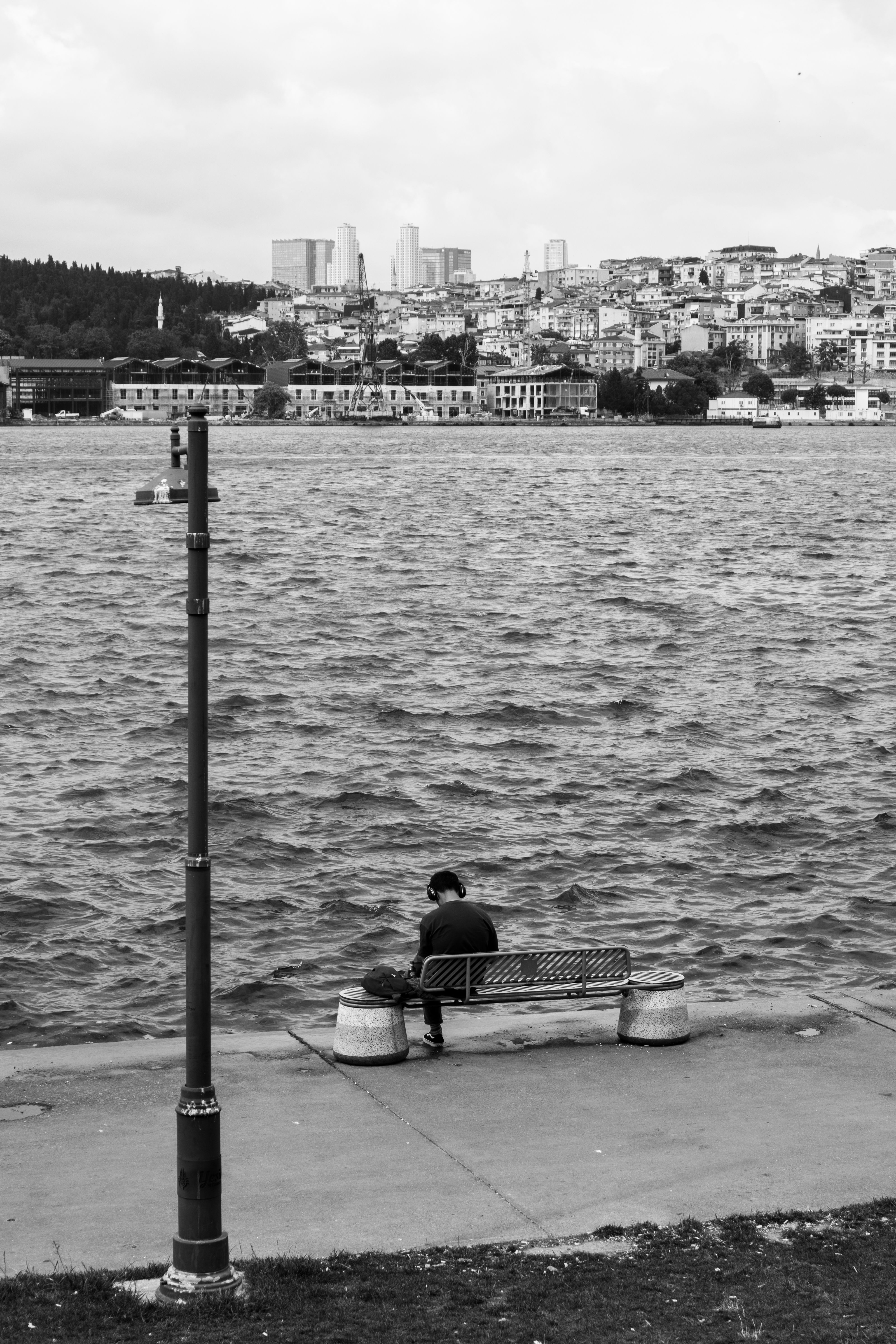 A Person Sitting on a Bench in City by a Body of Water · Free Stock Photo