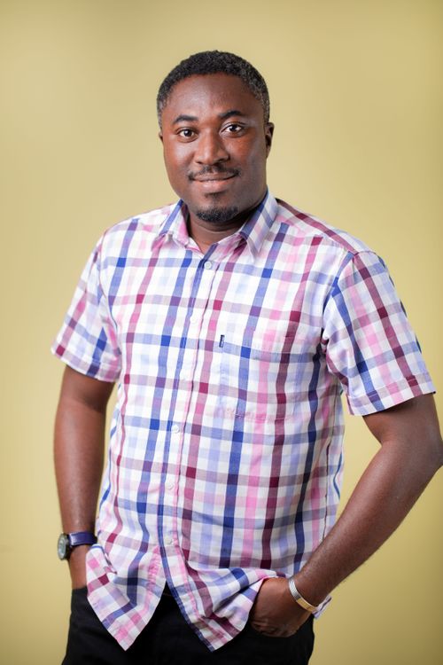 Free Portrait of a man in a checkered shirt standing confidently against a yellow background. Stock Photo