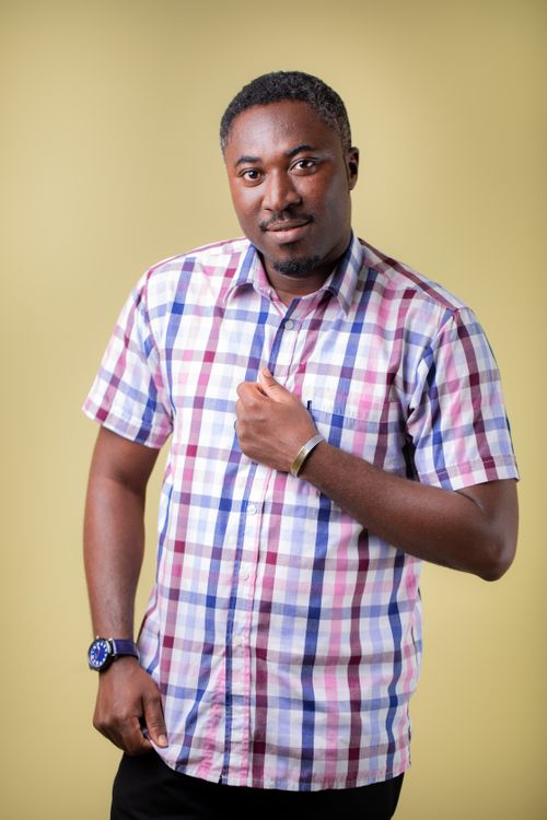Free Stylish portrait of a black man wearing a plaid shirt with a soft yellow background in a professional studio setting. Stock Photo