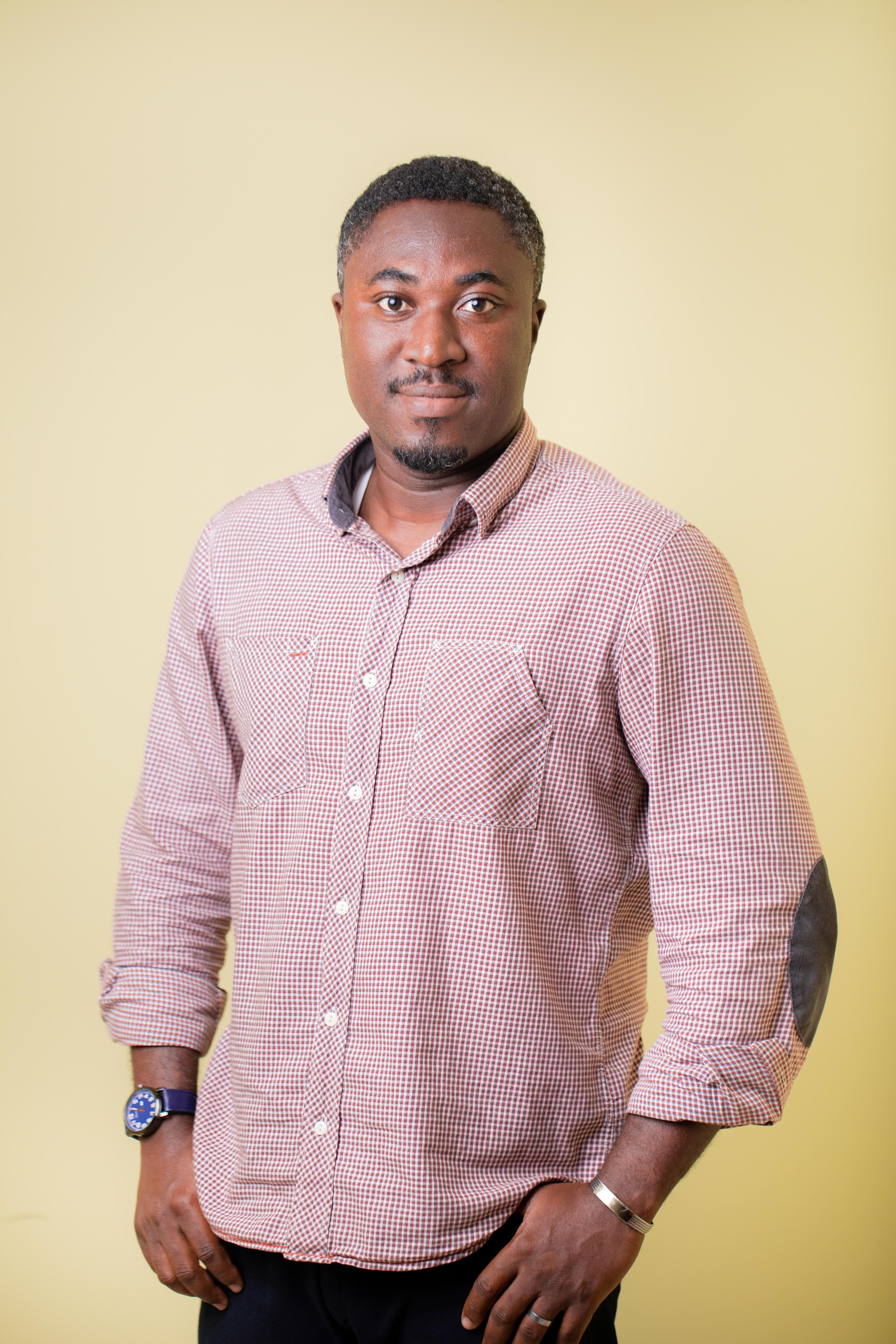 Fashionable portrait of a man in Accra, Ghana wearing a checkered shirt against a yellow background.