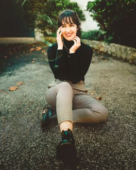 阳光明媚的日子里，一位穿着高领毛衣的女人微笑着盘腿坐在外面