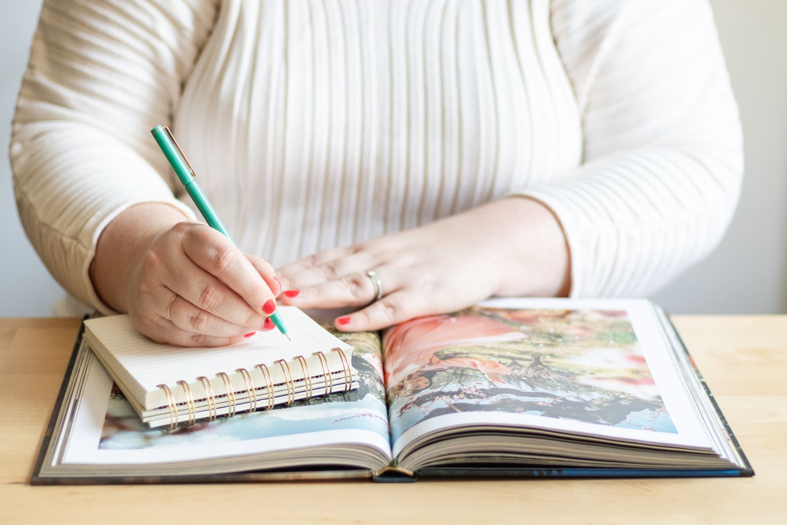 A person writing in a notebook beside an open book