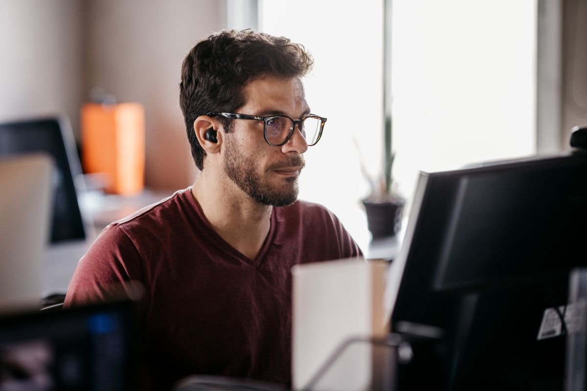 A developer working at a desktop workstation by a window. Photo by Jonathan Borba on Pexels