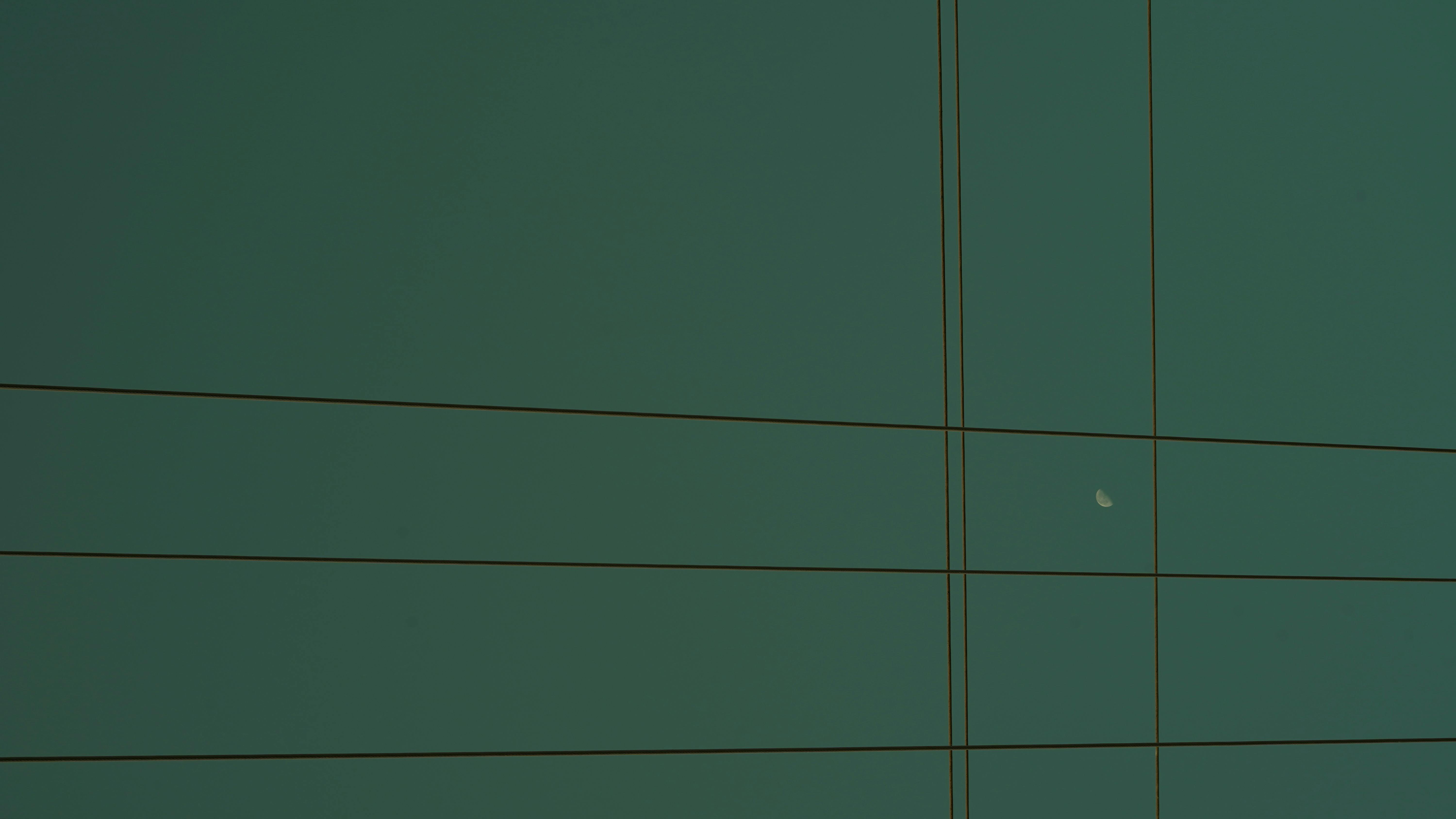 Free A minimalist view of the evening sky with power lines crossing and a visible moon. Stock Photo