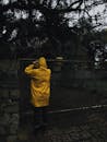 一个穿着黄色雨衣的人，在黑暗的雨天里站在门口，显得很神秘