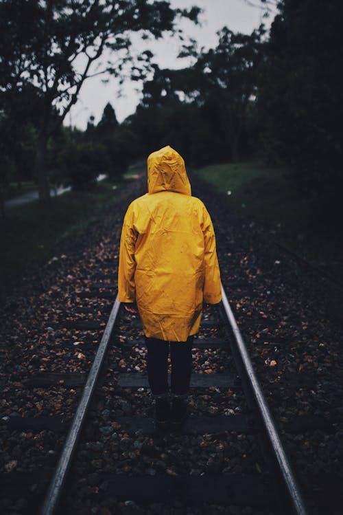 Foto Der Person, Die Regenmantel In Einer Eisenbahn Trägt