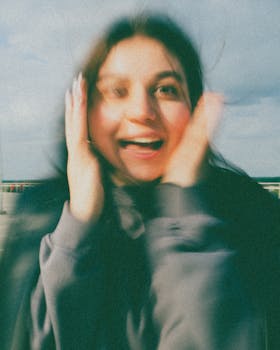 Blurred portrait of a young woman smiling outdoors with a sense of excitement.