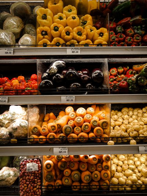 Free Vibrant array of vegetables neatly arranged on shelves at a Colombian grocery store. Stock Photo