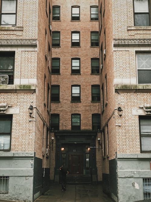 갈색 콘크리트 건물 사이에 서있는 사람