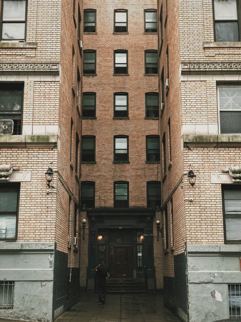 Vertical view of a narrow urban alley between brick apartment buildings with a central entrance doorway.