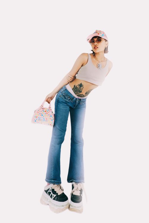 Free Stylish Asian woman posing in jeans and crop top, showcasing tattoos and urban fashion accessories. Stock Photo