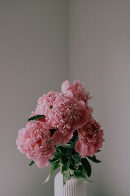 A serene bouquet of pink peonies elegantly arranged in a ceramic vase against a soft backdrop.