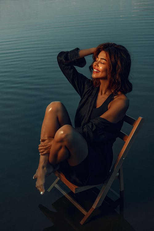 Smiling Woman Sitting on Chair on Water