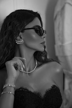 A glamorous woman posing with jewelry in a black and white fashion portrait.