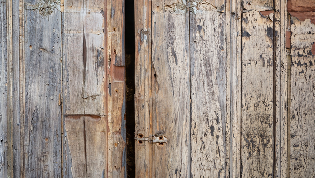 Closeup of a vintage wooden door with rustic texture, showcasing aged wood and peeling paint.
