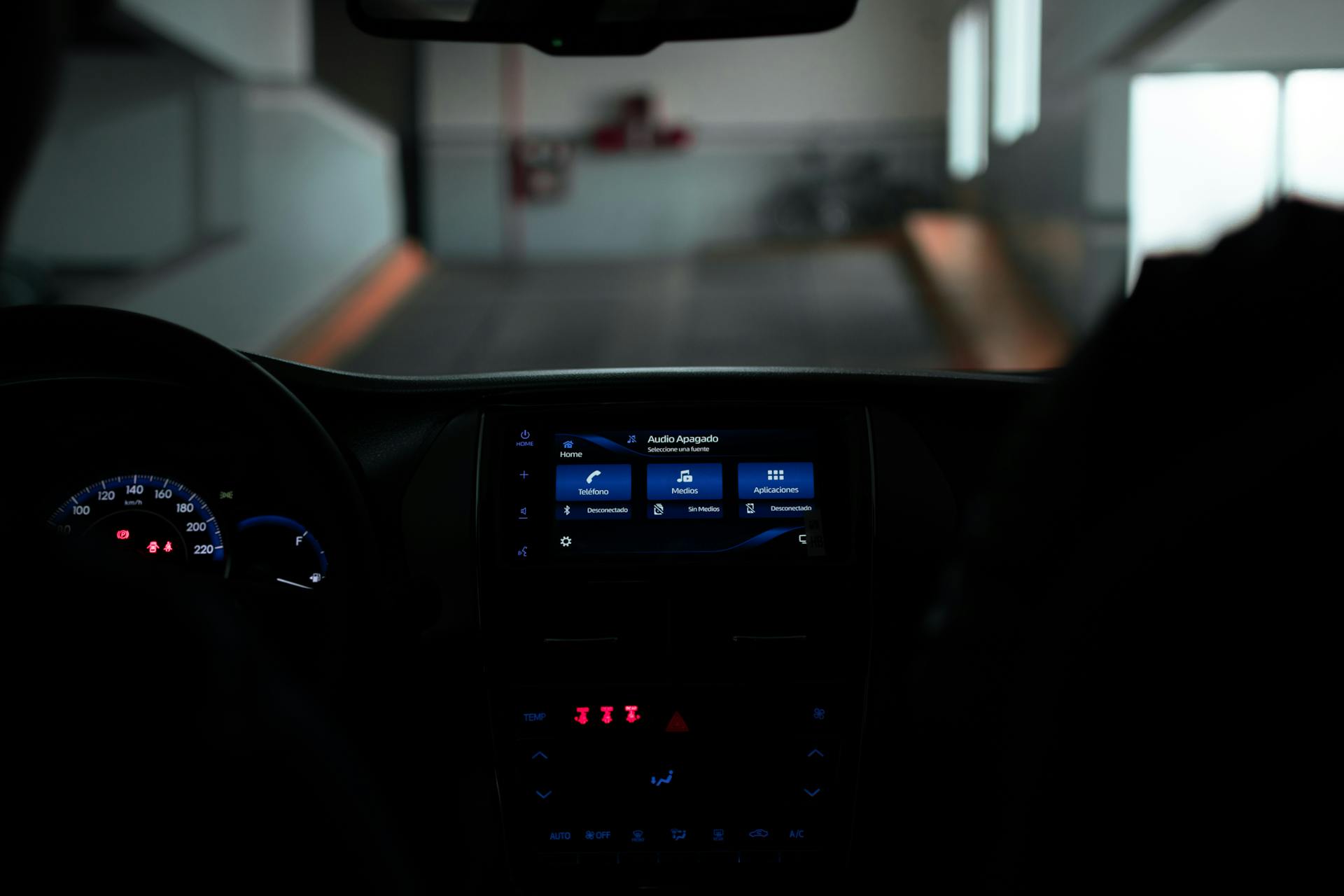 Interior view of a modern car's dashboard with illuminated controls and navigation screen.