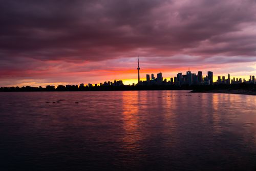 Free Beautiful view of Toronto skyline with CN Tower silhouetted against a vibrant sunset. Stock Photo
