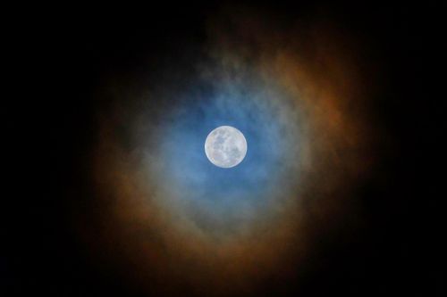 Free A striking full moon framed by vibrant clouds against a night sky. Stock Photo