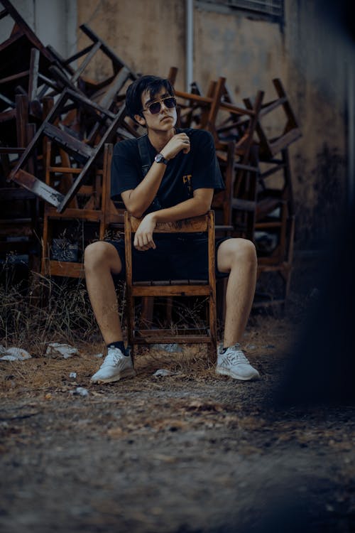 Man in Sunglasses Sitting among Chairs