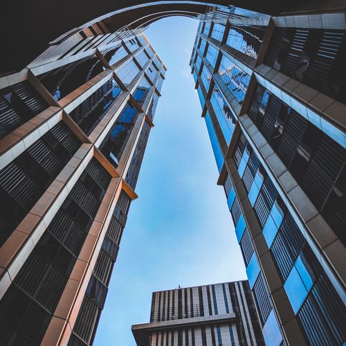 Free Low angle view of sleek skyscrapers with reflective glass facades against a clear blue sky. Stock Photo
