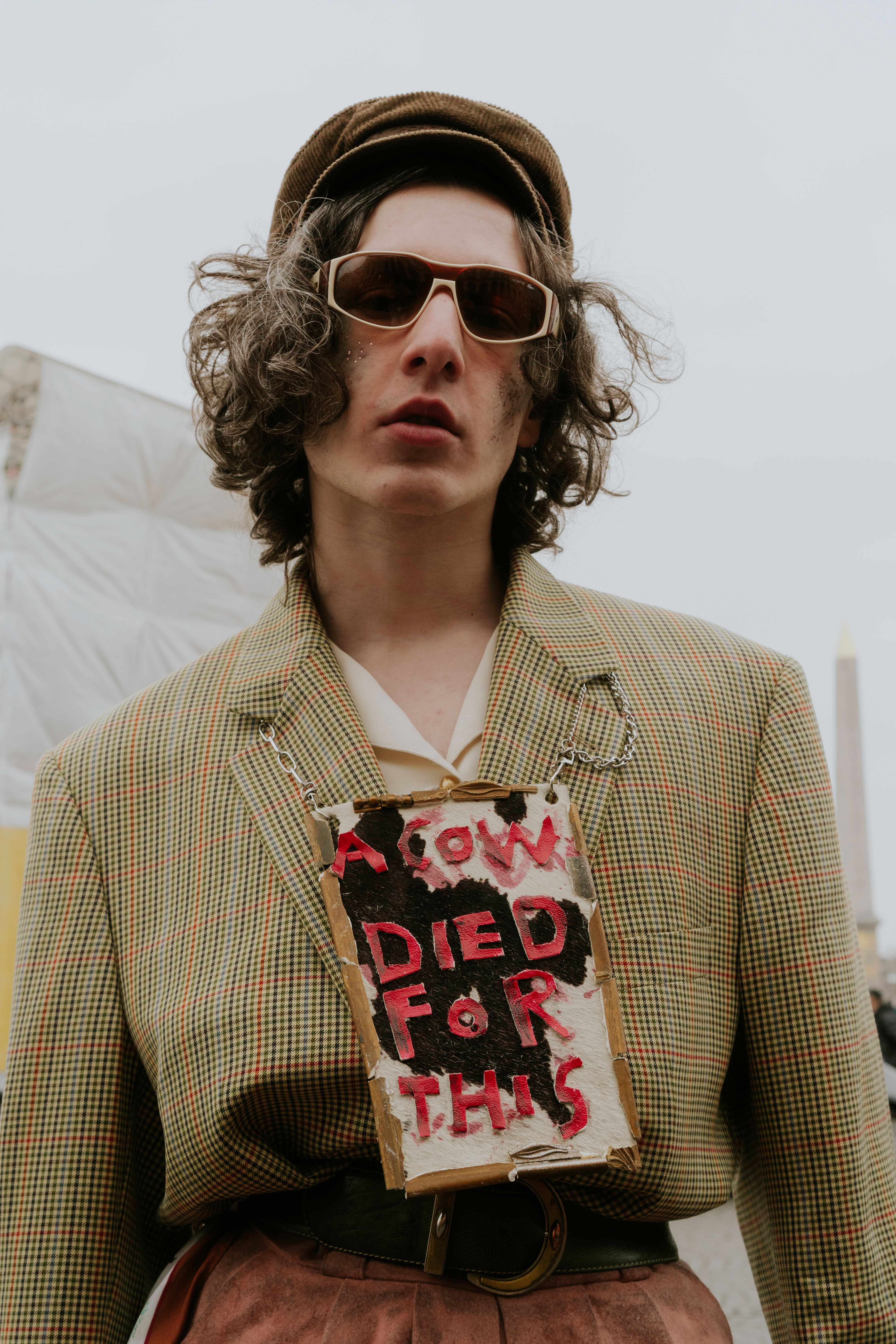 Fashionable individual at protest wearing vintage jacket with striking message.