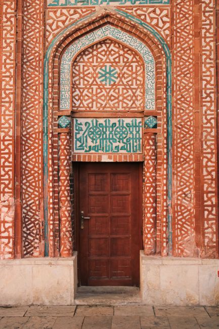 Ornate wooden door with detailed geometric Islamic patterns, an urban architectural piece.