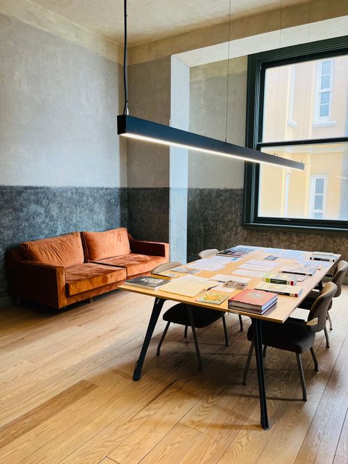 Free A contemporary room featuring an orange sofa, large table, and minimalist decor. Stock Photo