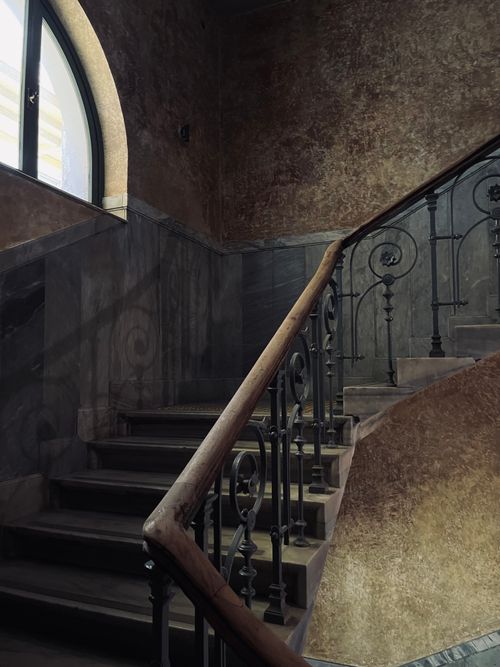 Free A beautifully crafted staircase showcasing classical architecture with iron railings and an arched window. Stock Photo